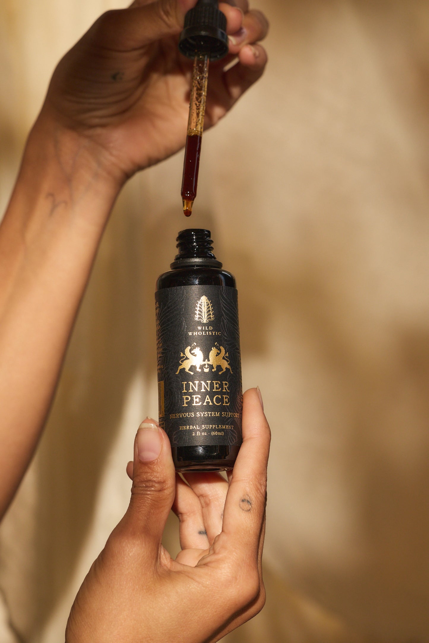 Hand holding a bottle of 'Inner Peace' with a dropper over a blurred background