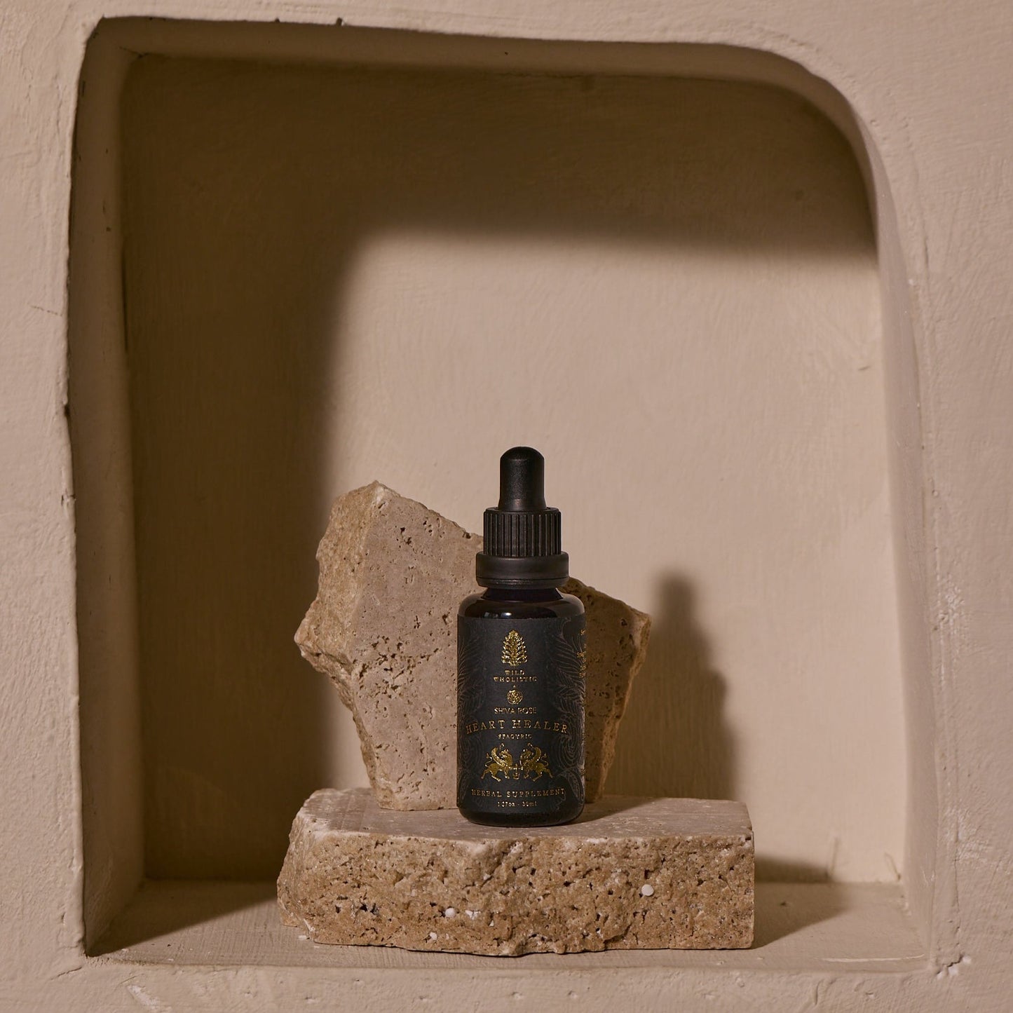 This image features a sophisticated presentation of the "Heart Healer" tincture. The product is displayed in a small, dark glass dropper bottle with a neatly printed label that highlights its botanical and healing properties.