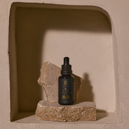 This image features a sophisticated presentation of the "Heart Healer" tincture. The product is displayed in a small, dark glass dropper bottle with a neatly printed label that highlights its botanical and healing properties.