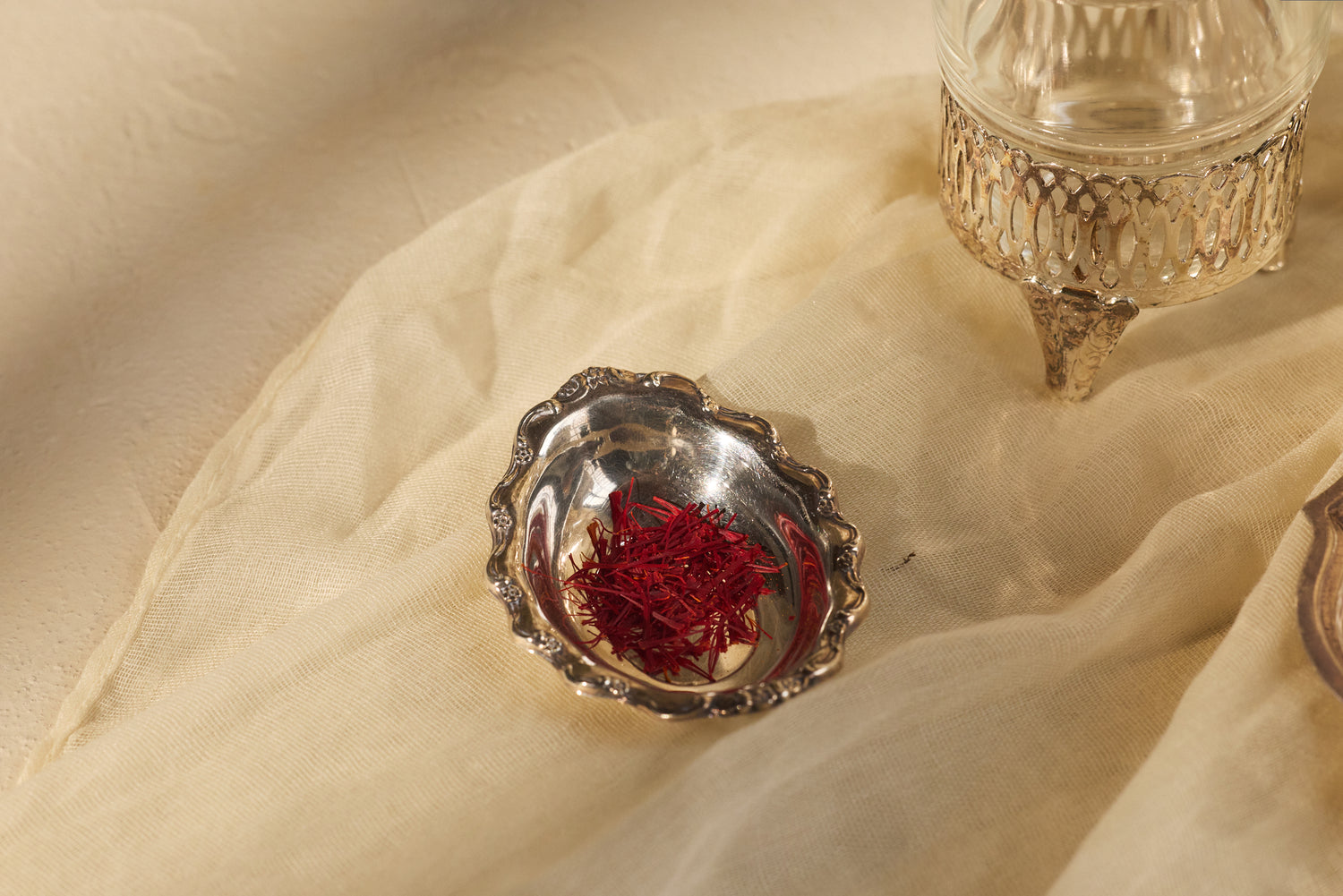 Silver dish with saffron on a beige fabric background.
