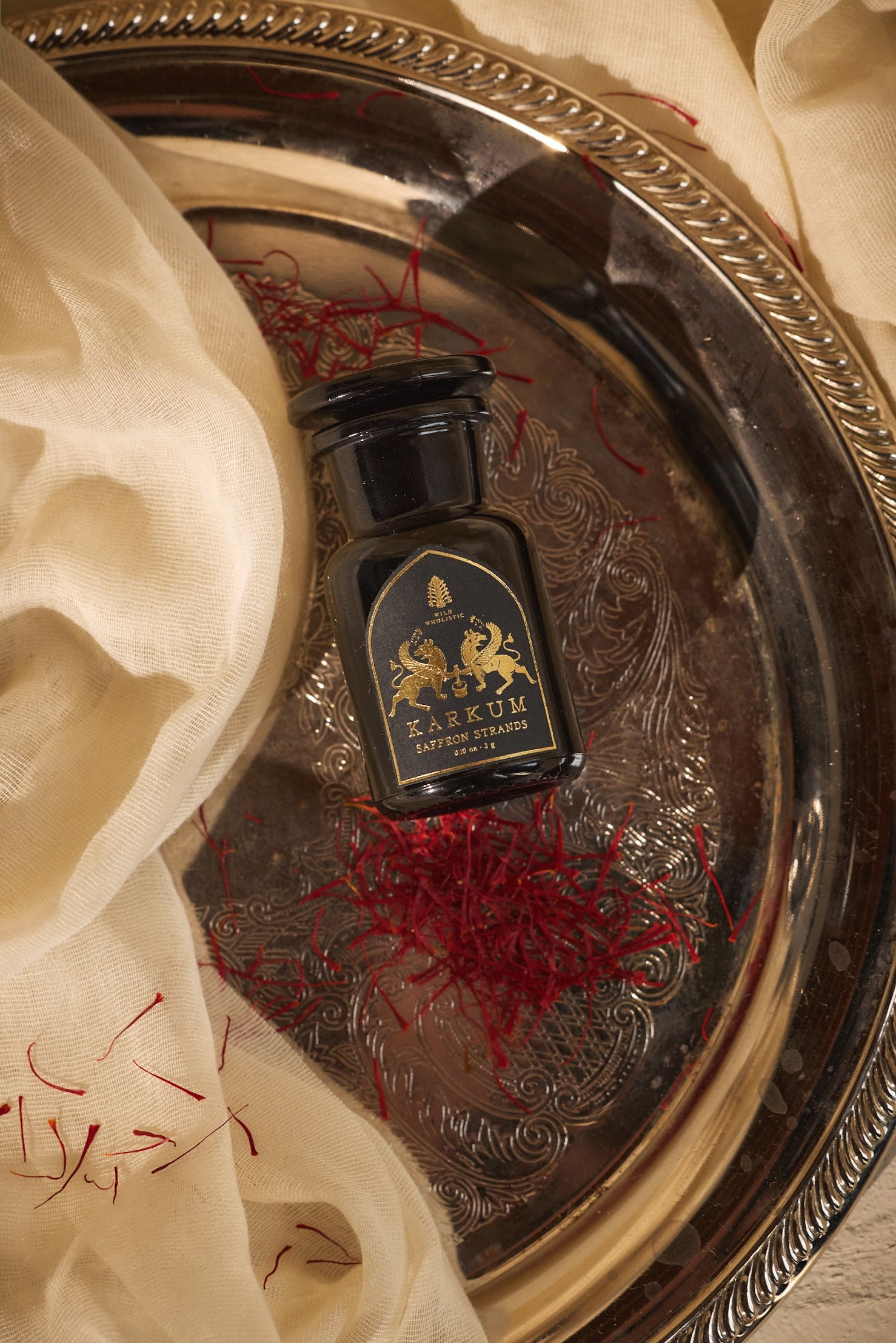 Bottle of Karkum on a decorative silver tray with saffron strands.