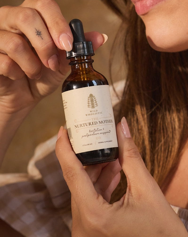 Woman holding herbal tincture bottle in warm natural light.
